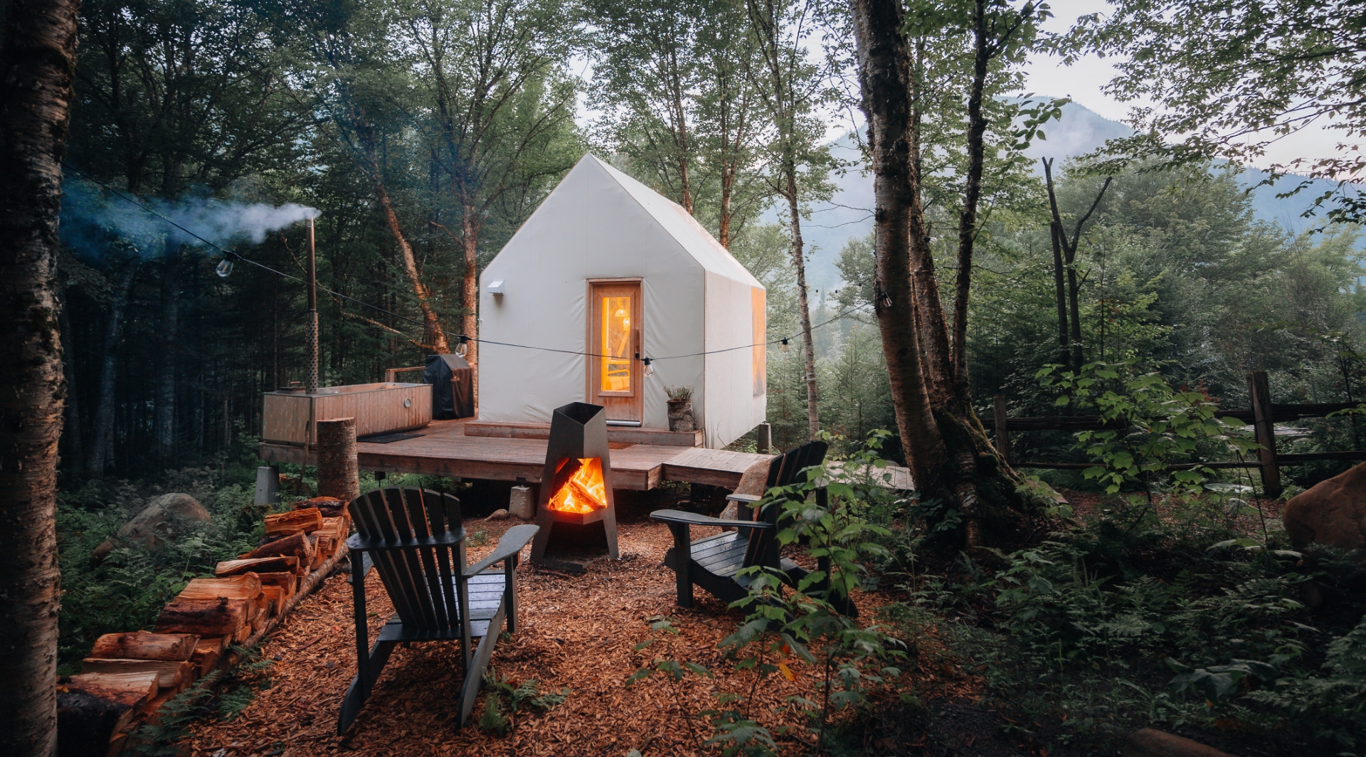 Noge Concept Chalet dans la foret feu à coté des chaises à l'extérieur